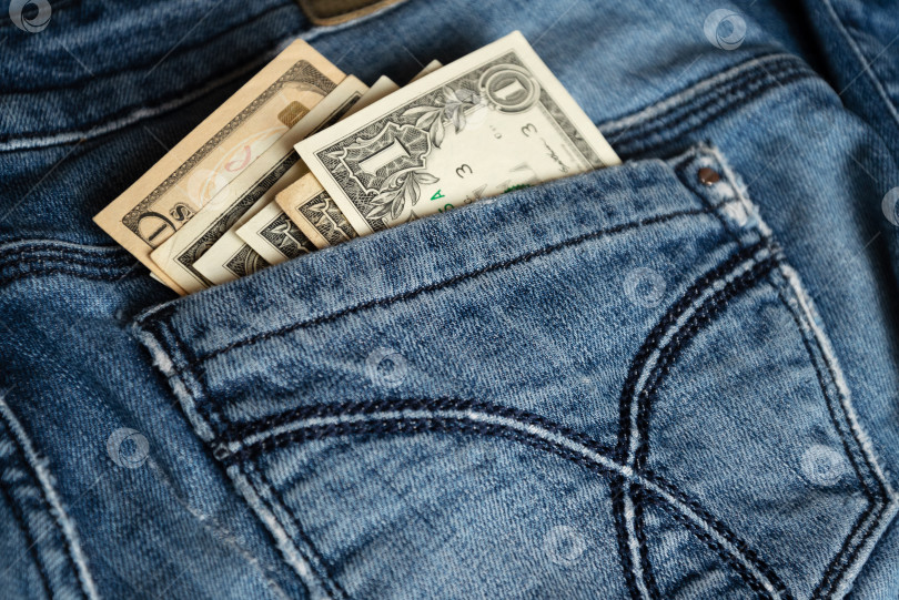 Скачать Из заднего кармана старых джинсов выглядывает несколько долларовых банкнот фотосток Ozero