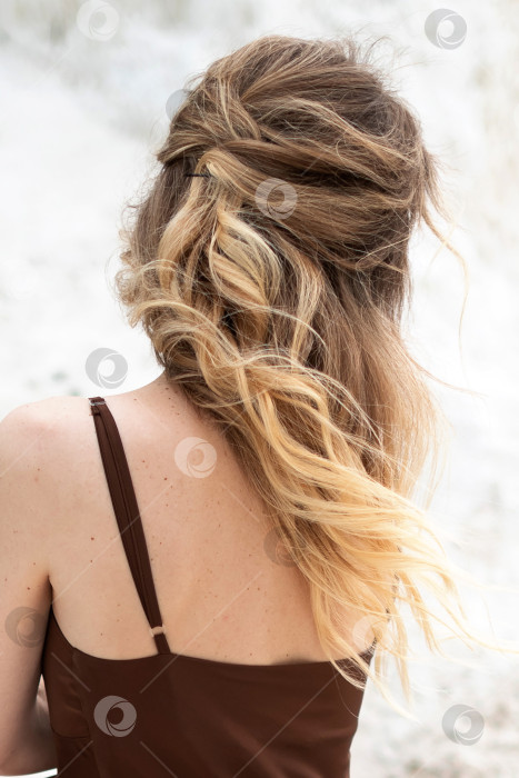 Скачать Молодая женщина с длинными светлыми уложенными волосами, одетая в коричневое шелковое платье, позирует стоя, отвернувшись фотосток Ozero