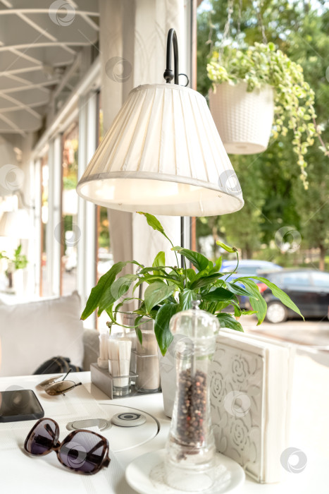 Скачать Сервированный стол, украшенный лампой и зеленым растением у окна в кафе фотосток Ozero