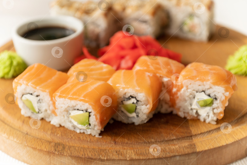 Скачать Набор вкуснейших суши-роллов Филадельфия с лососем, подаваемых на деревянной доске, японская кухня фотосток Ozero