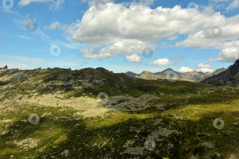 Скачать Остроконечные вершины горных хребтов с пологими скалистыми склонами под облачным летним небом. фотосток Ozero