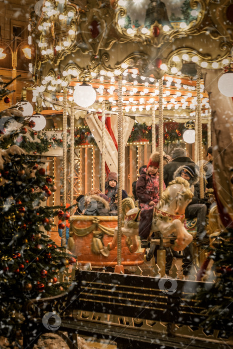 Скачать Дети катаются на ярко освещенной карусели во время рождественских каникул фотосток Ozero