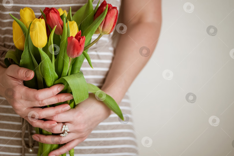 Скачать Женщина держит в руках букет свежих красных и желтых цветов тюльпана крупным планом фотосток Ozero