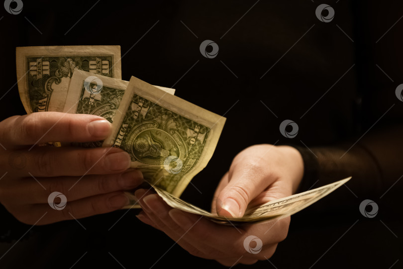 Скачать Женщина пересчитывает долларовые банкноты в своих руках, темный фон фотосток Ozero