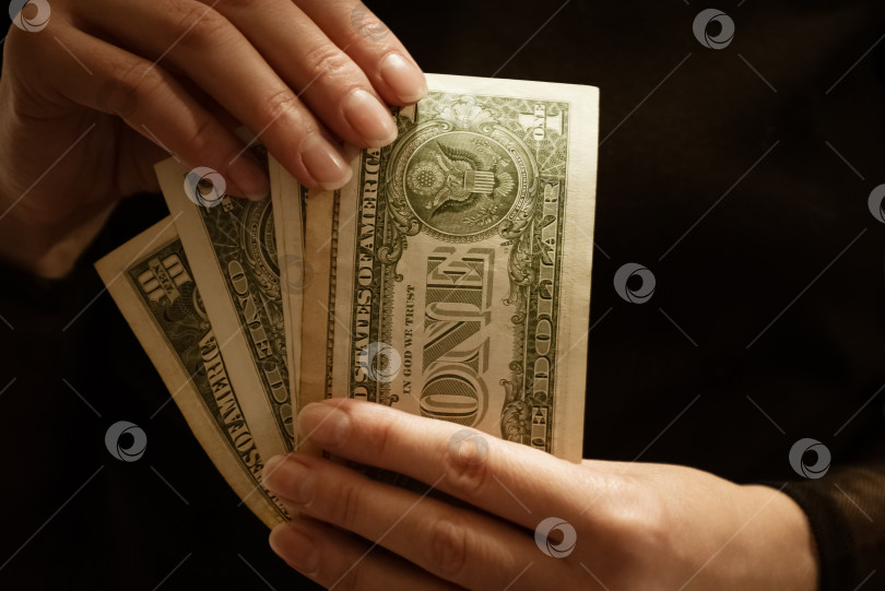 Скачать Женщина держит в руках несколько долларовых банкнот, темный фон фотосток Ozero