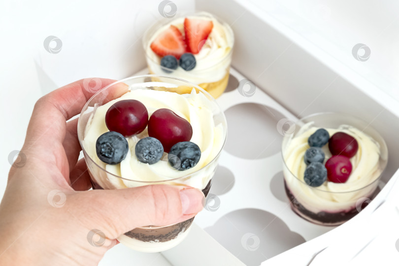 Скачать Человеческой рукой достаньте десерт со сливками и ягодами из полупустой коробки с набором фотосток Ozero