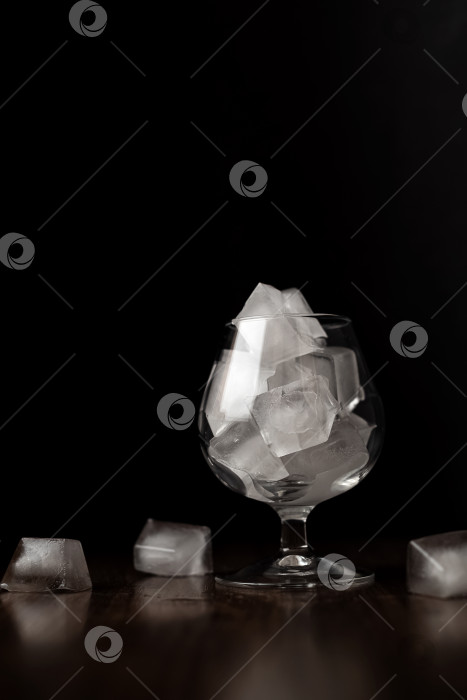 Скачать Бокал для вина, наполненный кубиками льда при мягком освещении на темном фоне фотосток Ozero