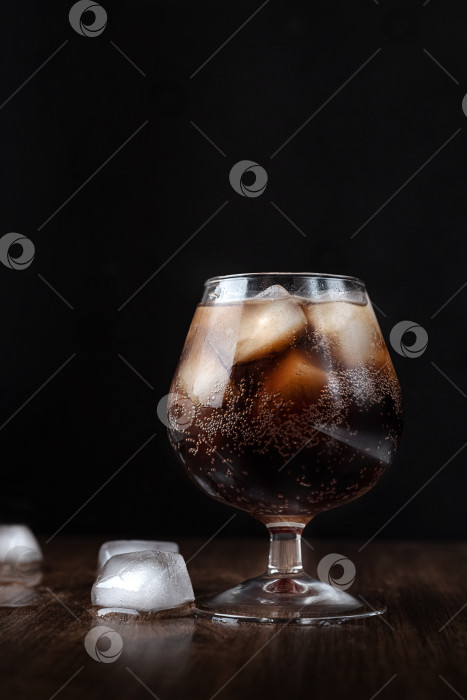 Скачать Бокал, наполненный тающими кубиками льда и игристым напитком на темном фоне фотосток Ozero