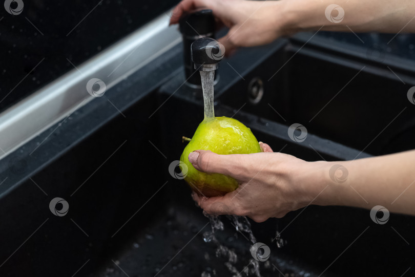 Скачать Человек моет яблоко под проточной водой в кухонной раковине фотосток Ozero