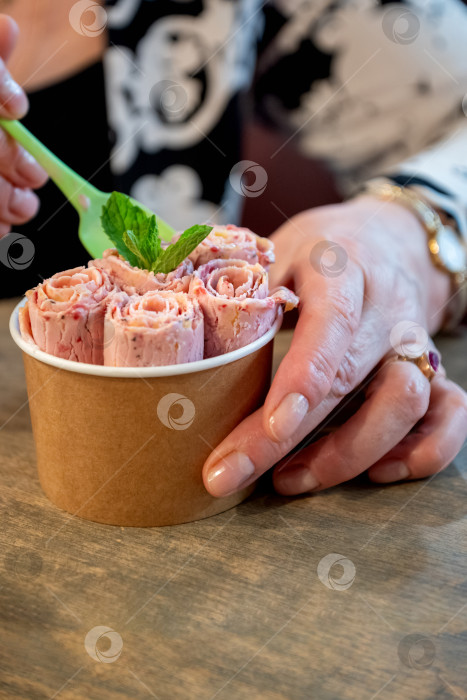 Скачать женщина ест мороженое в рулете, украшенное листиками свежей мяты, подается в стаканчике для выпечки фотосток Ozero