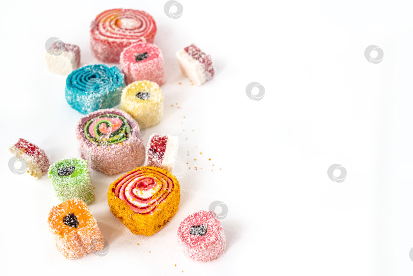 Скачать Разноцветные желейные конфеты разной формы разбросаны по белому фону фотосток Ozero