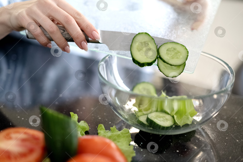 Скачать Процесс приготовления овощного салата, перекладывание ломтиков огурца в стеклянную миску. Здоровое веганское питание и образ жизни фотосток Ozero