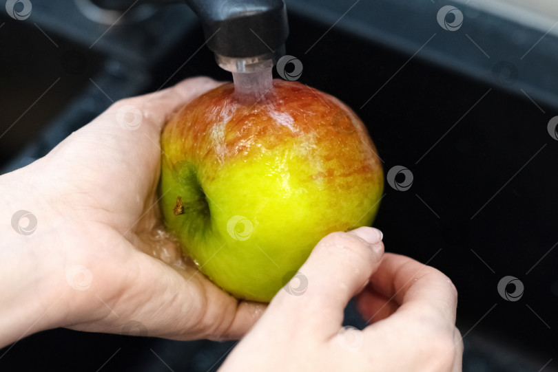 Скачать Человек моет яблоко под проточной водой в кухонной раковине фотосток Ozero