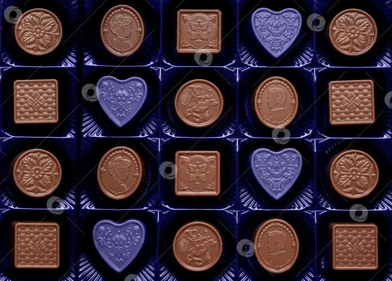 Скачать Набор шоколадных конфет разной формы с очень необычным фоном из конфет в форме сердца фотосток Ozero