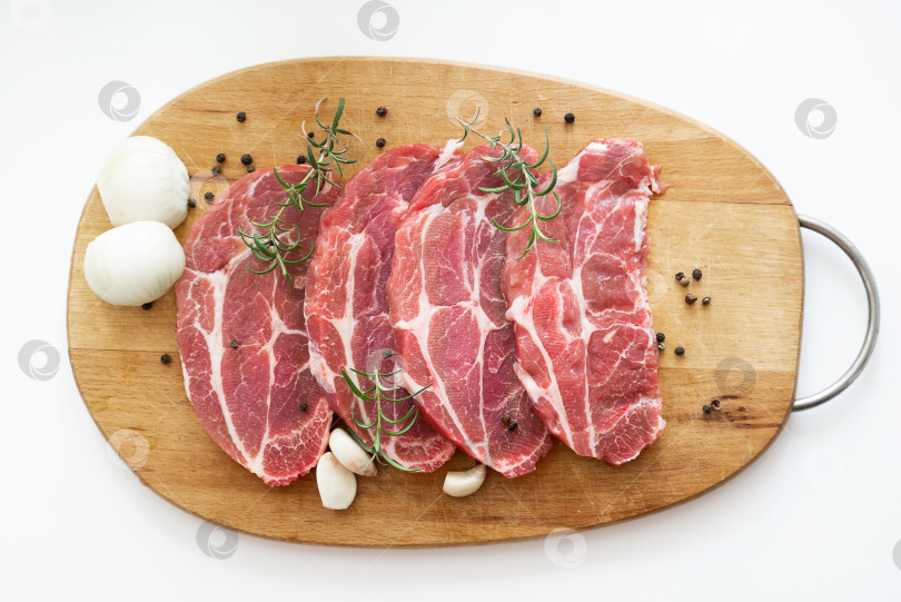 Скачать Вид сверху на нарезанное сырое свиное мясо со специями на деревянной разделочной доске фотосток Ozero