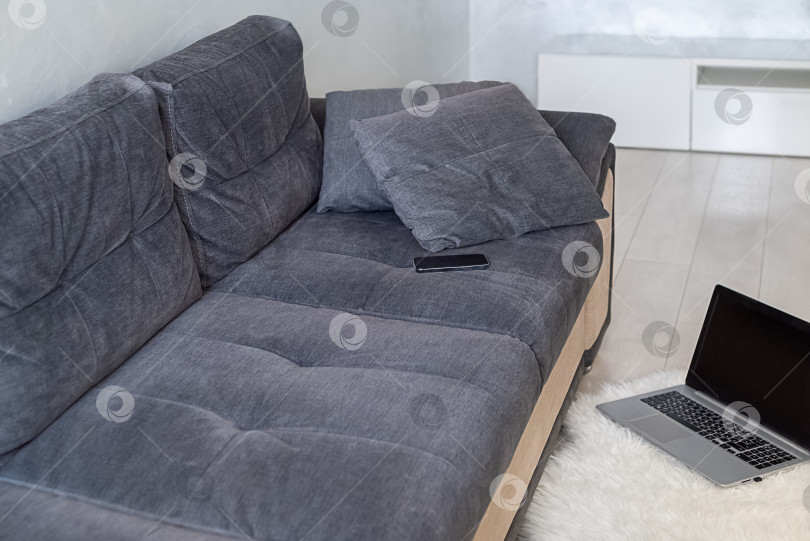 Скачать Минималистичный интерьер квартиры с диваном и ноутбуком, лежащим на полу фотосток Ozero
