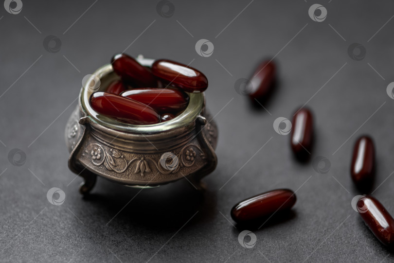 Скачать капсулы с лекарством в серебряной чаше на темном фоне фотосток Ozero
