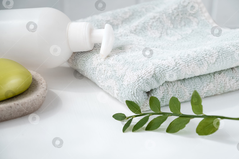 Скачать Белый столик в ванной со свежим полотенцем, органическим оливковым мылом на подносе и дозатором косметики. Концепция личной гигиены и охраны здоровья фотосток Ozero