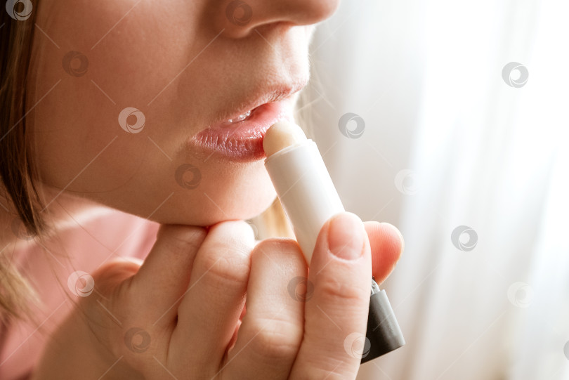 Скачать Молодая женщина наносит увлажняющий бальзам на губы фотосток Ozero
