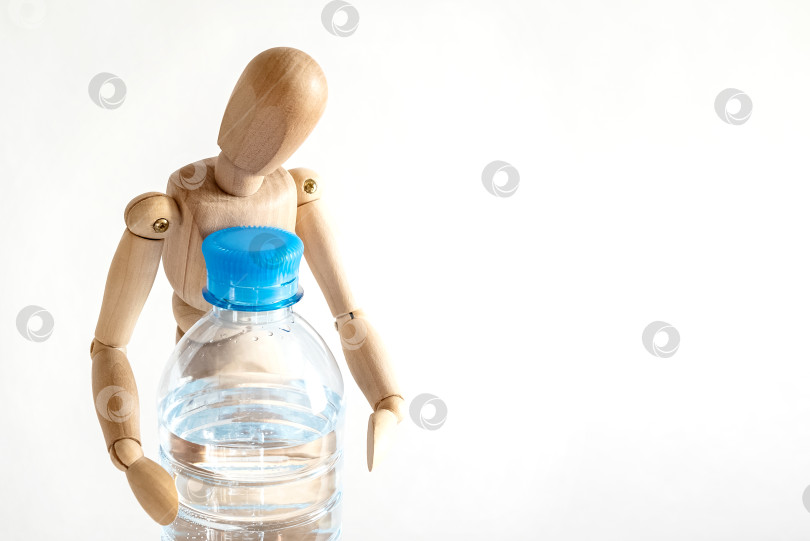 Скачать Деревянный манекен держит пластиковую бутылку с водой. Питьевая вода, здоровый образ жизни фотосток Ozero