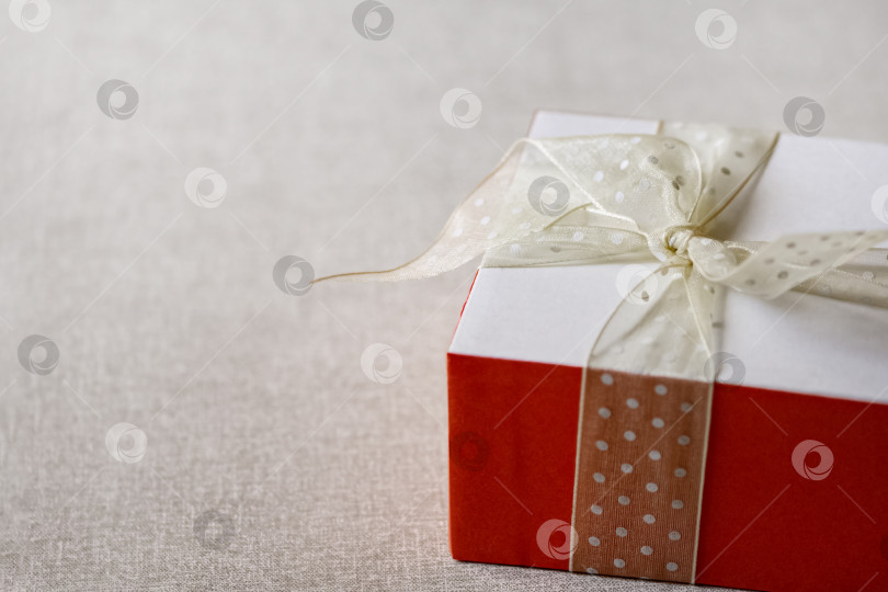 Скачать Подарочная коробка, обернутая белым бантом на нейтральном фоне фотосток Ozero