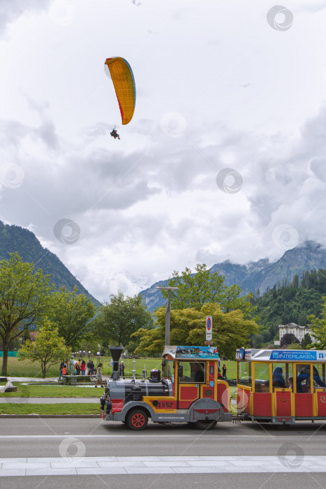 Скачать Парапланерист и туристы в Интерлакене, Швейцария фотосток Ozero