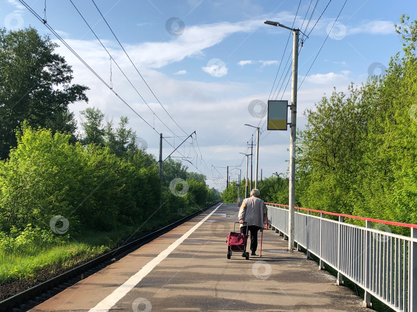 Скачать одинокий пожилой мужчина с тележкой для багажа на пустой железнодорожной платформе фотосток Ozero