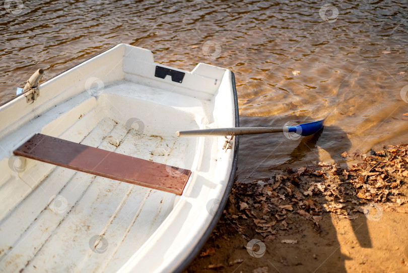Скачать старая лодка с веслами лежит на берегу озера на фоне ряби озерной воды фотосток Ozero