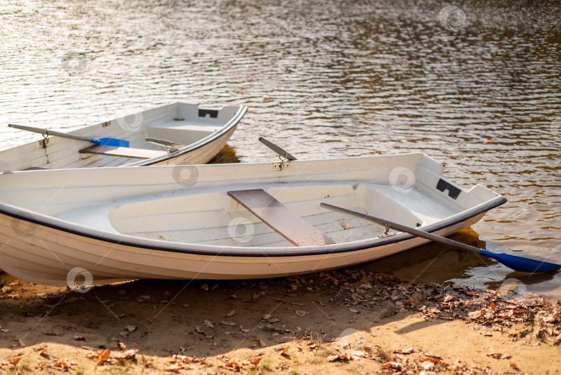 Скачать Две старые лодки с веслами лежали на берегу озера на фоне ряби озерной воды фотосток Ozero