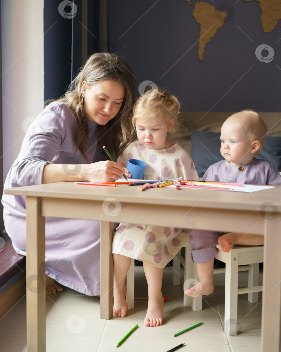 Скачать Заботливая молодая мама учит рисовать двух своих маленьких детей фотосток Ozero