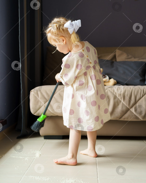 Скачать Милая маленькая девочка подметает пол метлой дома фотосток Ozero