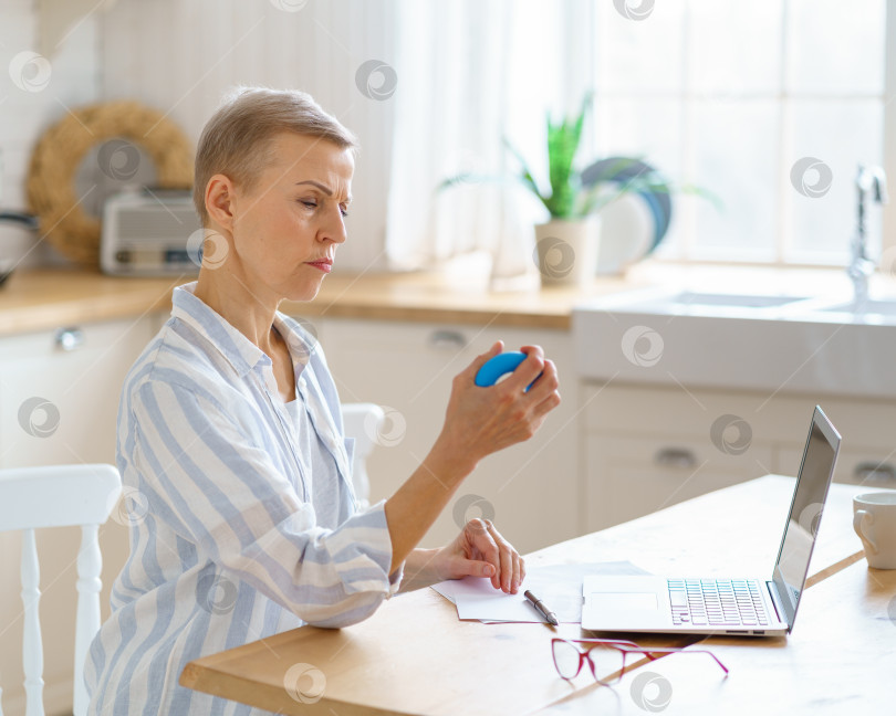 Скачать Портрет зрелой женщины, тренирующейся с резиновым круглым кольцом для захвата во время работы онлайн из дома фотосток Ozero