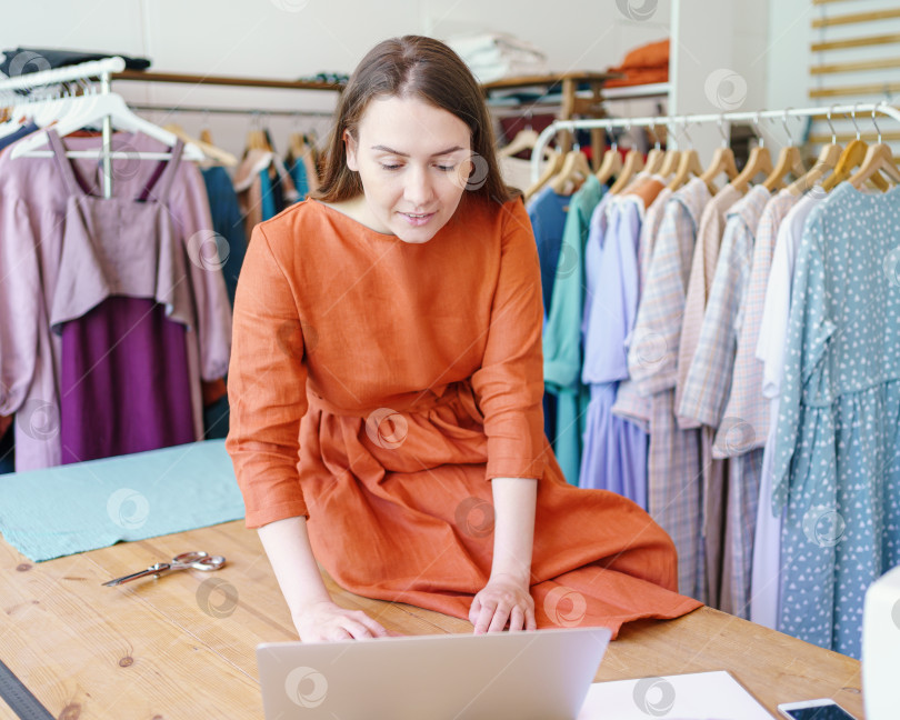 Скачать Женщина-модельер, создающая дизайн одежды онлайн на ноутбуке фотосток Ozero