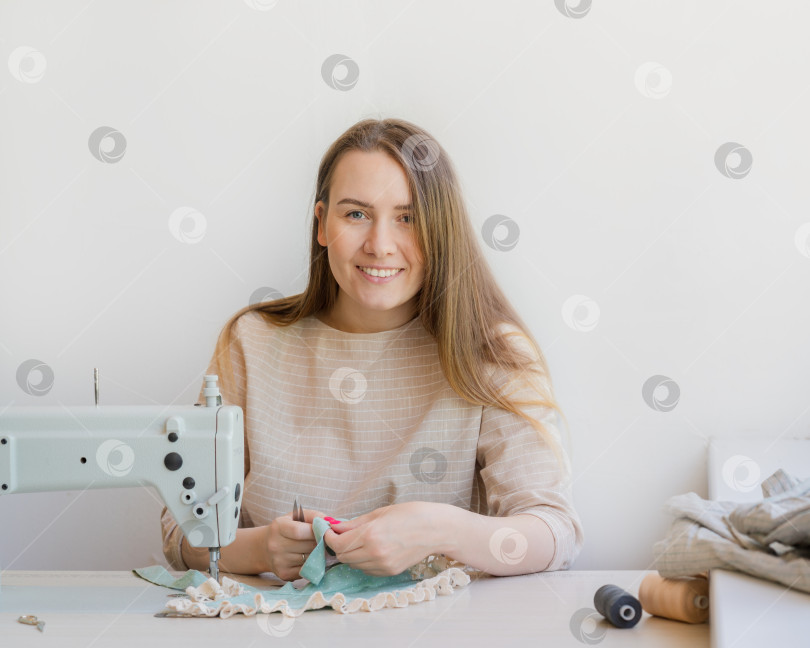 Скачать Счастливая женщина-владелица ателье, работающая на рабочем месте со швейной машинкой фотосток Ozero