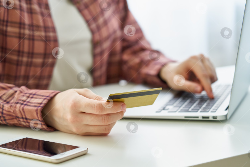 Скачать Безликая женщина расплачивается дебетовой картой, делая покупки в Интернете на ноутбуке фотосток Ozero