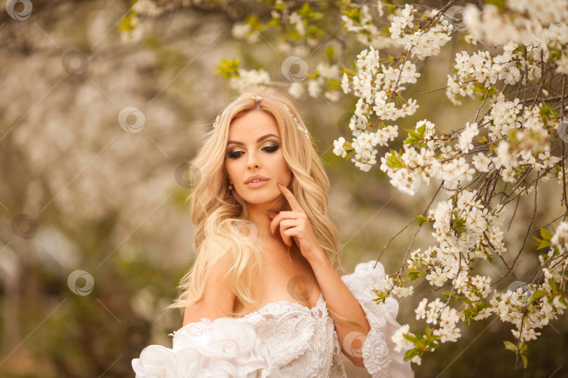 Скачать Светлый цветущий сад. Женщина в белом платье прогуливается по цветущему вишневому саду. фотосток Ozero