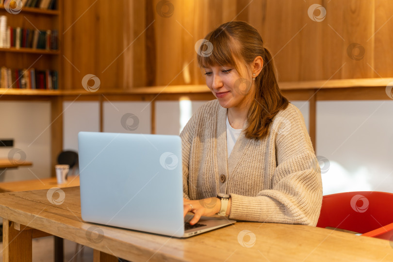 Скачать Молодая счастливая женщина за ноутбуком в кафе. Удаленная работа вдали от дома. Горизонтальный фотосток Ozero