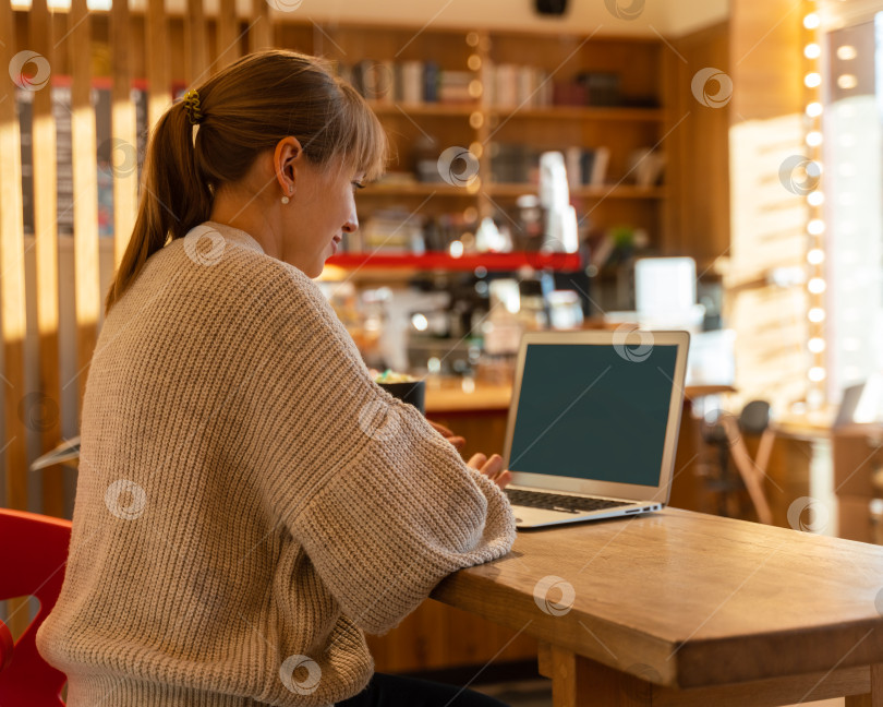 Скачать Удаленная работа и учеба в кофейне. Девушка, использующая ноутбук с пустым пространством фотосток Ozero