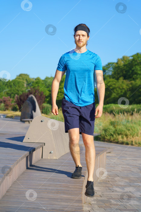 Скачать Молодой спортивный парень в спортивной одежде занимается спортом на открытом воздухе солнечным летним днем фотосток Ozero