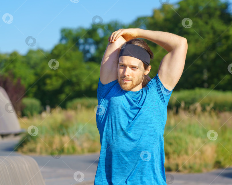 Скачать Молодой спортивный мужчина в спортивной одежде разминается на природе в солнечный день фотосток Ozero