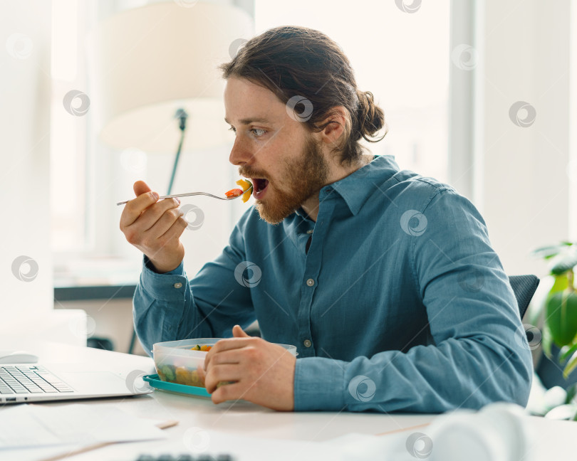 Скачать Голодный мужчина наслаждается веганской едой во время обеденного перерыва фотосток Ozero
