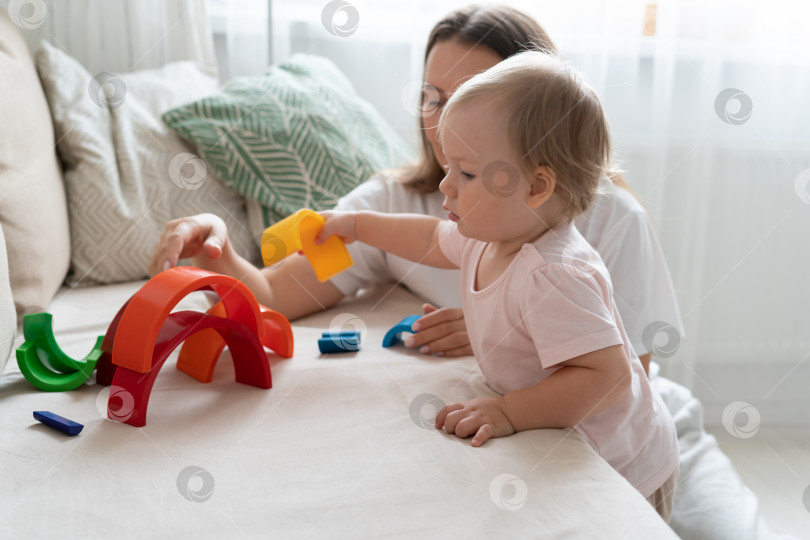 Скачать Мать играет с ребенком в пластиковые игрушки на диване. Развитие ребенка и досуг дома фотосток Ozero