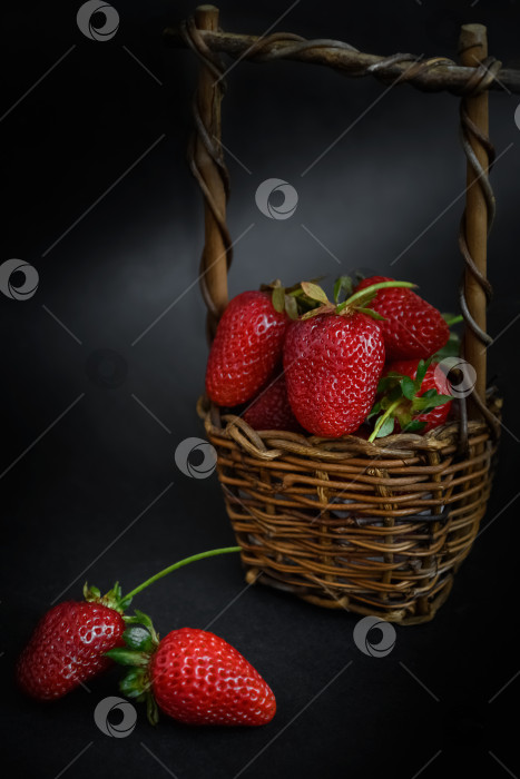 Скачать Плетеная корзинка, полная красной спелой клубники на темной поверхности, летняя еда фотосток Ozero