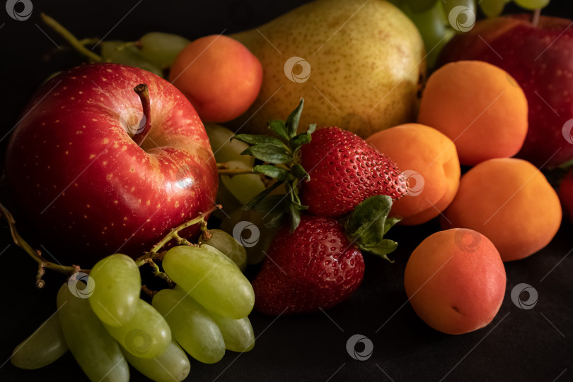 Скачать На столе ассортимент свежих сочных фруктов, таких как яблоко, абрикос, груша, виноград и клубника. фотосток Ozero