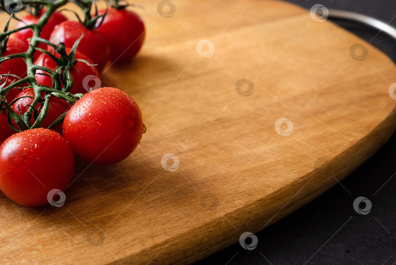 Скачать Красные спелые свежие помидоры черри на ветке на деревянной разделочной доске фотосток Ozero