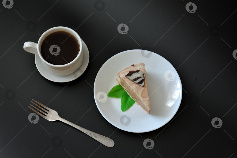 Скачать Тарелка с кусочком крем-чизкейка с мятой на черном фоне, рядом вилка и чашка горячего черного кофе на блюдце. фотосток Ozero