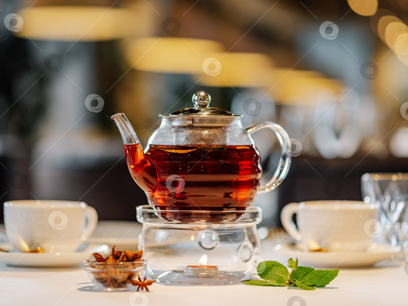 Скачать Стеклянный чайник с грелкой на столе в ресторане фотосток Ozero