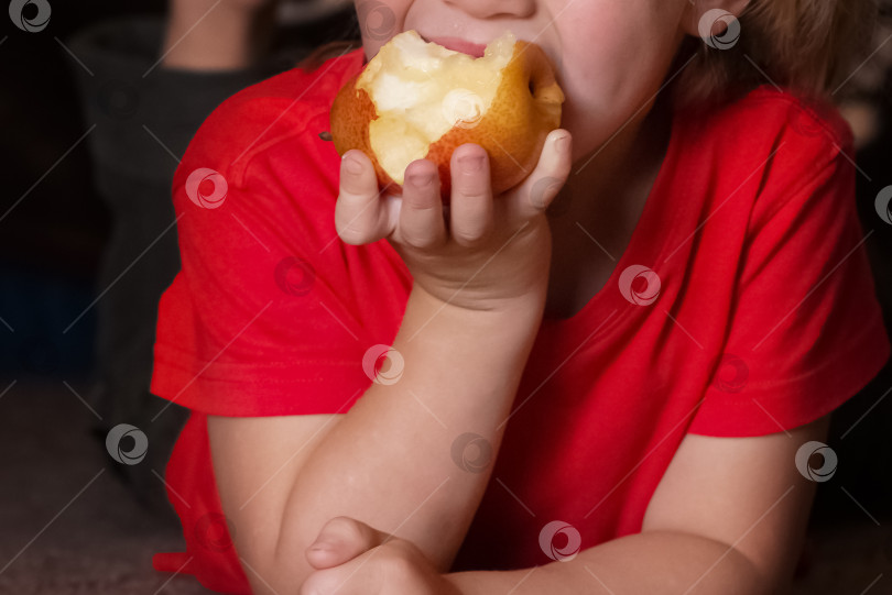 Скачать ребенок в красной футболке ест спелую грушу фотосток Ozero
