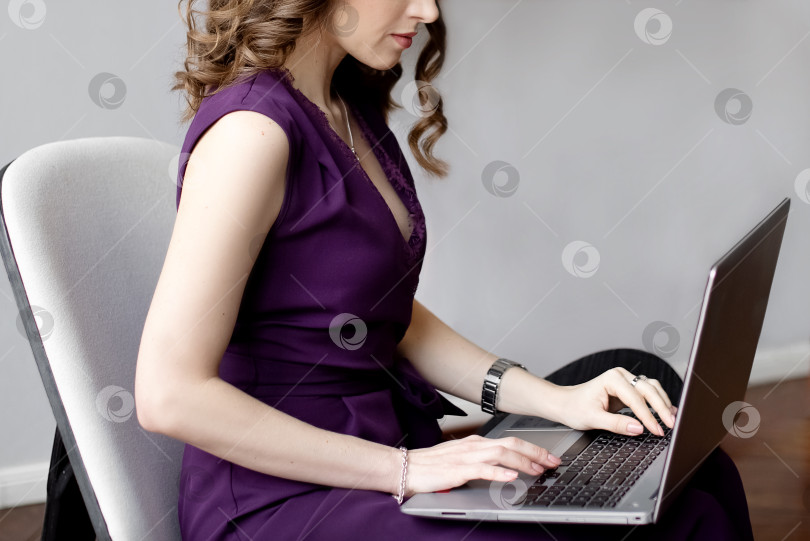 Скачать Крупным планом молодая женщина работает за ноутбуком, лежащим у нее на коленях фотосток Ozero