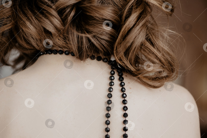 Скачать Молодая женщина с короткими вьющимися волосами и черными бусами на шее, вид сзади фотосток Ozero